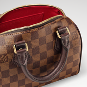 Louis Vuitton Speedy Bandoulière 20, sac Louis Vuitton compact avec doubles poignées Toron, fermeture zippée et bandoulière ajustable.