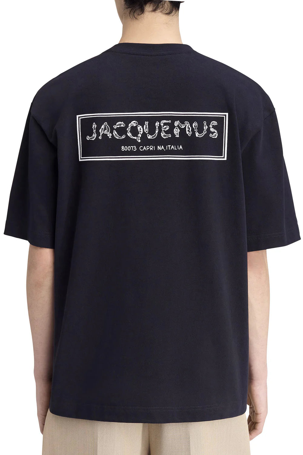 TEE SHIRT JACQUEMUS BLEU MARINE AVEC UN LOGO "J" EN FORME DE POISSON SUR LE COEUR ET UN GROS CADRE INSCRIT JACQUEMUS AU DOS DU TEE-SHIRT