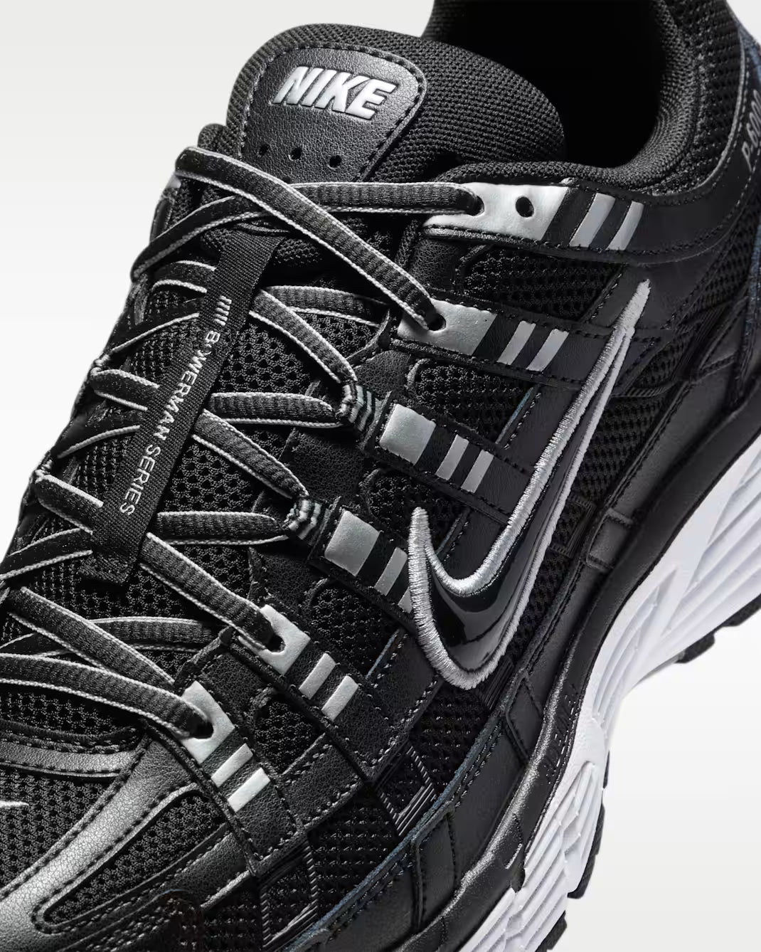Vue zoomée sur les détails latéraux de la Nike P-6000 Black White Metallic Silver noire, blanche et argentée avec mesh respirant, renforts superposés et détails Metallic Silver 