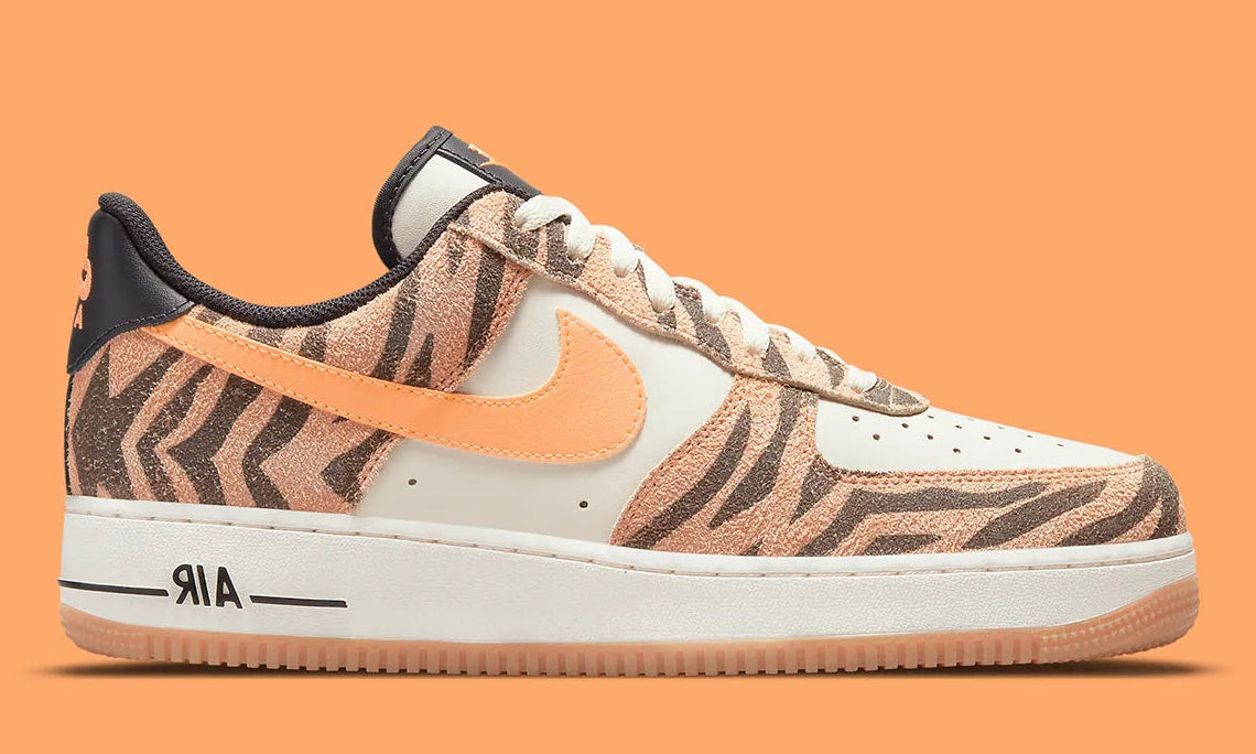 Nike Air Force 1 Low Daktari, sneaker en cuir Coconut Milk avec empiècements en suède zébré orange, Swoosh orange et semelle gomme.