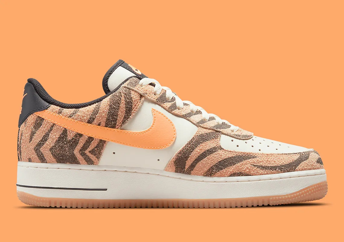 Nike Air Force 1 Low Daktari, sneaker en cuir Coconut Milk avec empiècements en suède zébré orange, Swoosh orange et semelle gomme.