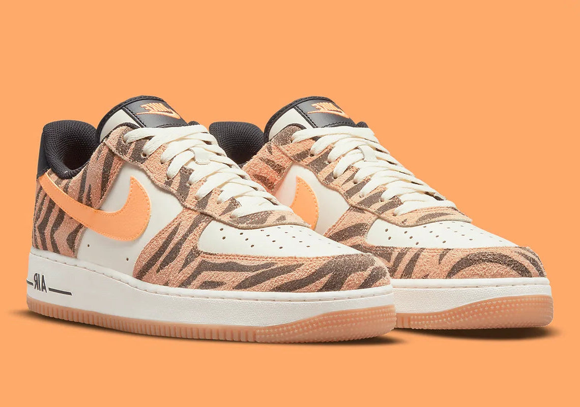 Nike Air Force 1 Low Daktari, sneaker en cuir Coconut Milk avec empiècements en suède zébré orange, Swoosh orange et semelle gomme.