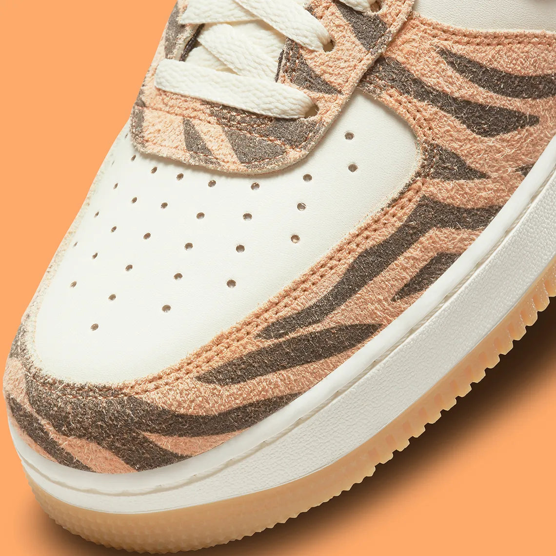 Nike Air Force 1 Low Daktari, sneaker en cuir Coconut Milk avec empiècements en suède zébré orange, Swoosh orange et semelle gomme.