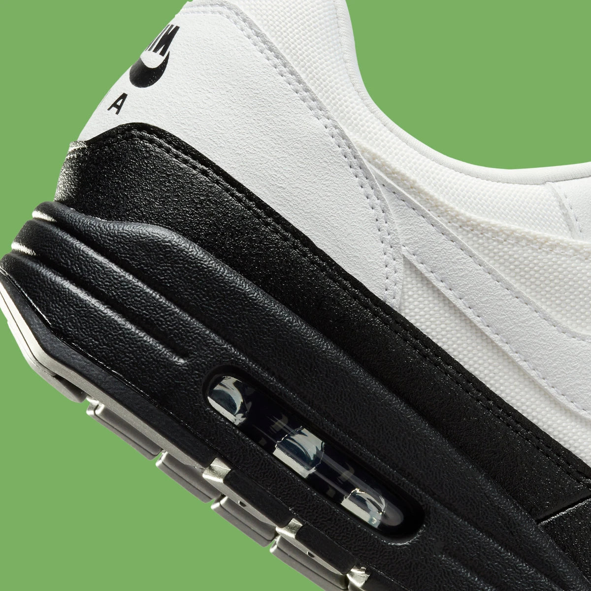 Sneakers Nike Air Max 1 White Black Chlorophyll en matériaux premium avec unité Air visible et détails contrastés iconiques vue zoomée sur les détails arrière de la paire. 