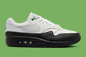 Sneakers Nike Air Max 1 White Black Chlorophyll en matériaux premium avec unité Air visible et détails contrastés iconiques vue de profil. 