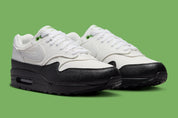Sneakers Nike Air Max 1 White Black Chlorophyll en matériaux premium avec unité Air visible et détails contrastés iconiques vue de 3/4 face. 
