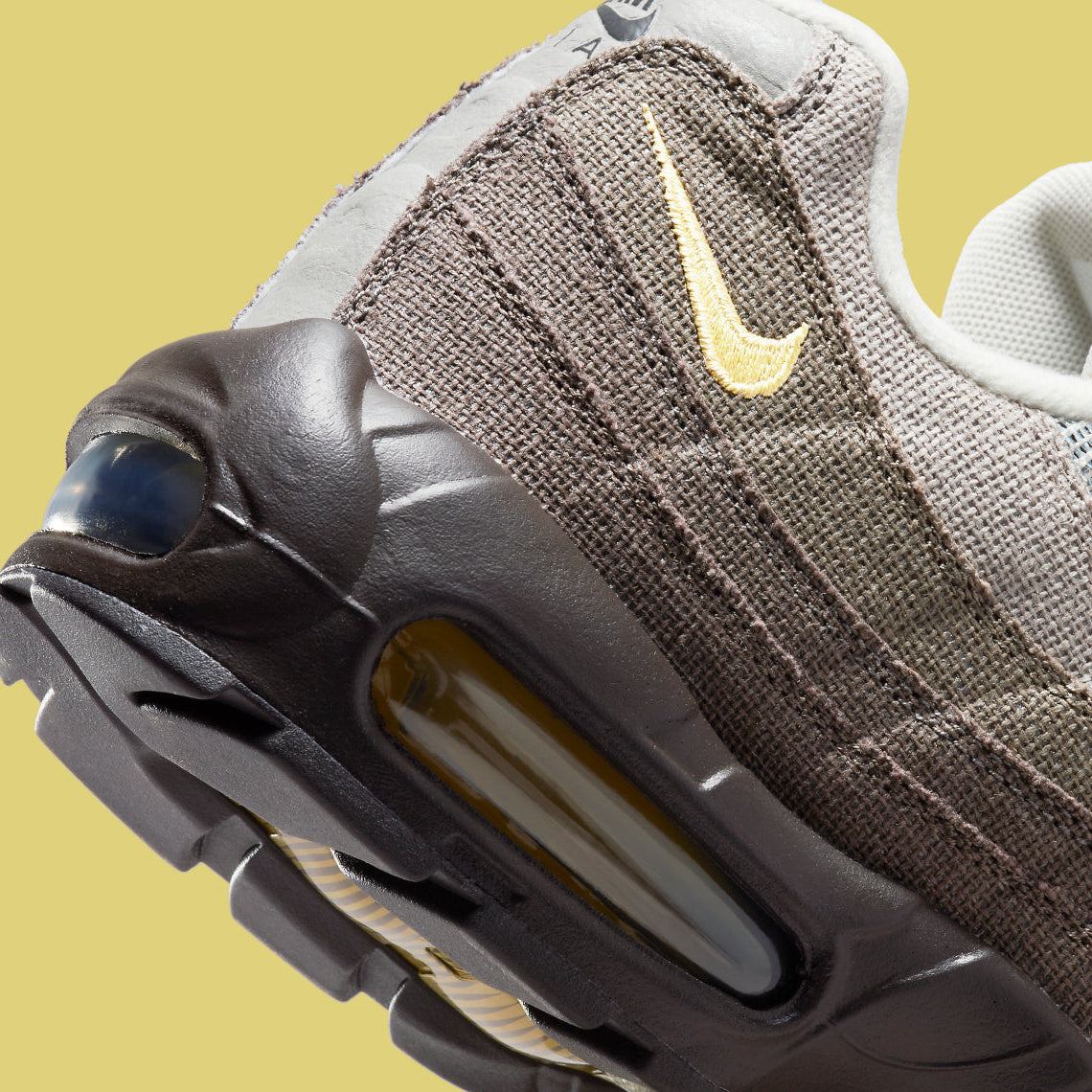 Vue zoomée sur les détails arrières de la Nike Air Max 95 NH Ironstone en tons brun, taupe et Olive Grey avec panneaux en textile jacquard, détails Celery et unités Air-Sole visibles.
