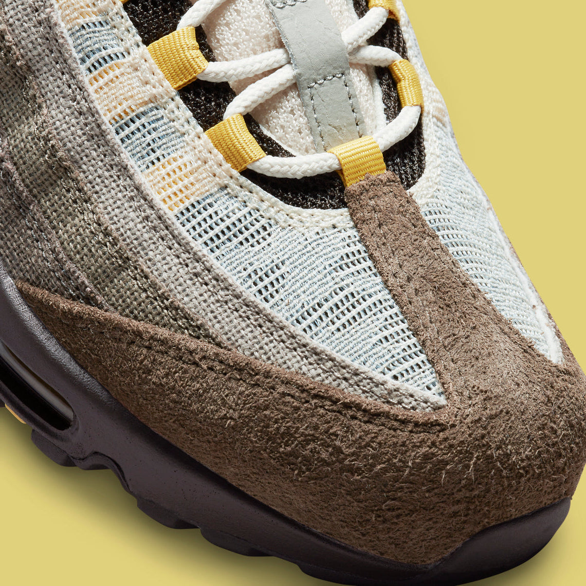 Vue zoomée sur les détails avants de la Nike Air Max 95 NH Ironstone en tons brun, taupe et Olive Grey avec panneaux en textile jacquard, détails Celery et unités Air-Sole visibles.