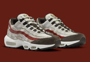 Nike Air Max 95 Social FC DQ9016-001, sneaker beige, marron et bordeaux avec motif camouflage, écusson football et unités Nike Air visibles.