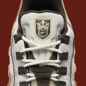 Nike Air Max 95 Social FC DQ9016-001, sneaker beige, marron et bordeaux avec motif camouflage, écusson football et unités Nike Air visibles.