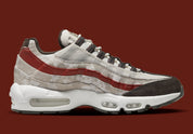 Nike Air Max 95 Social FC DQ9016-001, sneaker beige, marron et bordeaux avec motif camouflage, écusson football et unités Nike Air visibles.