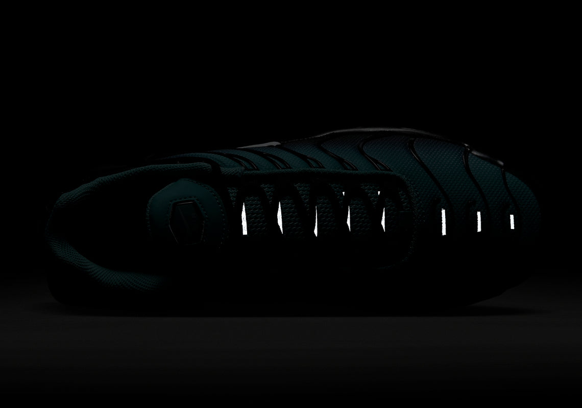 Image de la Nike Air Max Plus “Light Retro Blue”, sneaker en mesh turquoise à noir dégradé, overlay TPU noir ondulé, mini Swoosh blanc, bulles Tuned Air visibles, silhouette TN. Vue avant de nuit