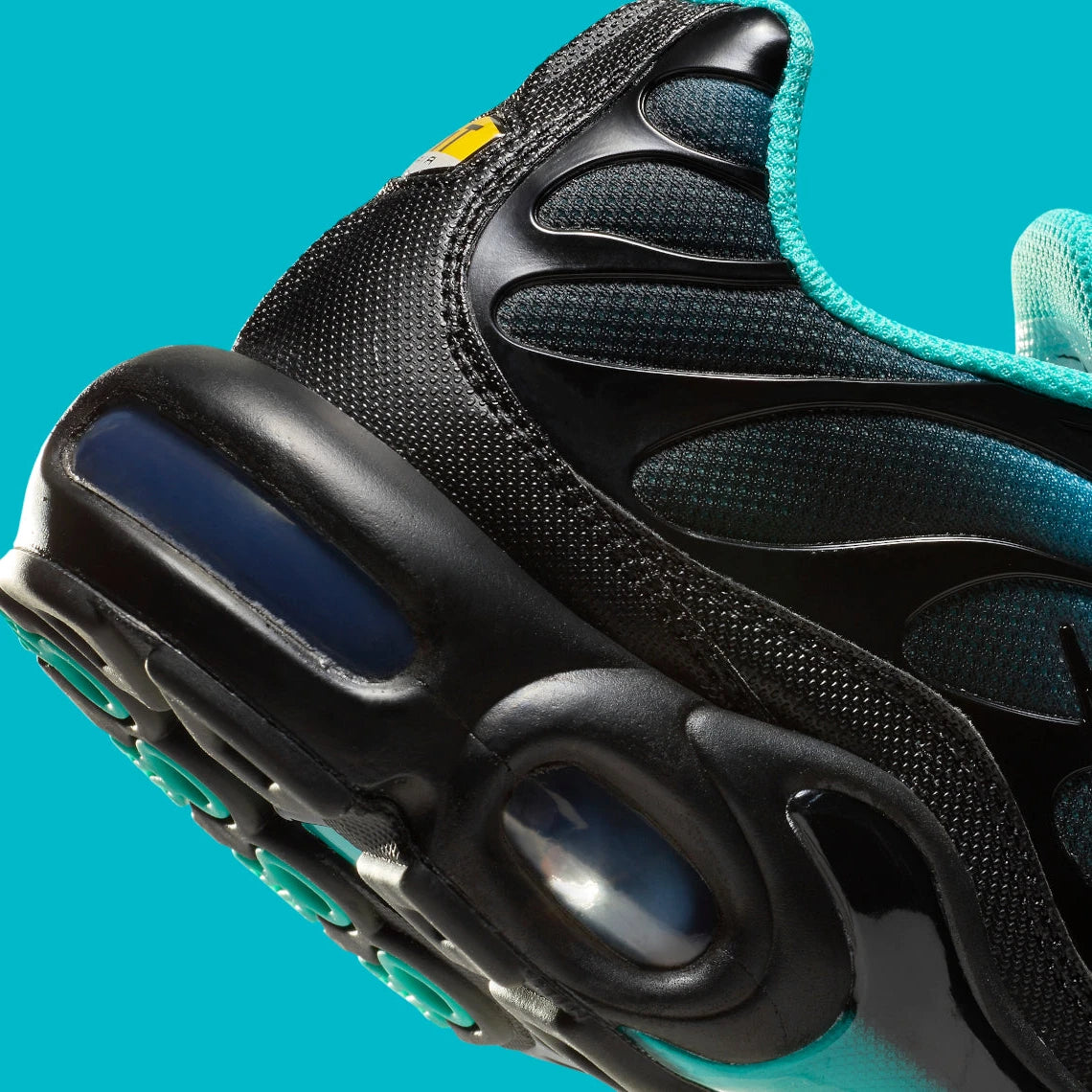 Image de la Nike Air Max Plus “Light Retro Blue”, sneaker en mesh turquoise à noir dégradé, overlay TPU noir ondulé, mini Swoosh blanc, bulles Tuned Air visibles, silhouette TN. Vue zoomer arrière 