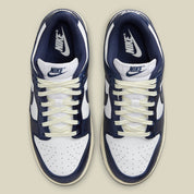 Nike Dunk Low PRM Vintage Navy, sneaker en cuir blanc et bleu marine avec Swoosh bleu et semelle crème effet vintage.