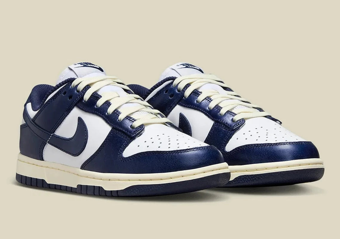 Nike Dunk Low PRM Vintage Navy, sneaker en cuir blanc et bleu marine avec Swoosh bleu et semelle crème effet vintage.