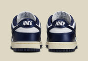 Nike Dunk Low PRM Vintage Navy, sneaker en cuir blanc et bleu marine avec Swoosh bleu et semelle crème effet vintage.
