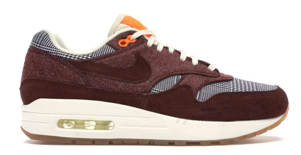 Image de la Nike Air Max 1 Houndstooth Bronze Eclipse, sneaker en mesh blanc cassé avec empiècements pied-de-poule, suede sable, détails Bronze Eclipse et unité Air visible.