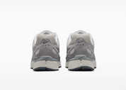 Nike P-6000 SE Pure Platinum Wolf Grey Summit White grise et blanche avec textile respirant, renforts en cuir synthétique et semelle en mousse vue de derrière. 