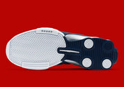 Nike Shox BB4 Olympics avec tige en cuir synthétique blanc et nubuck bleu marine, détails Metallic Silver, amorti Zoom Air à l'avant-pied et quatre colonnes Nike Shox au talon.