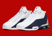 Nike Shox BB4 Olympics avec tige en cuir synthétique blanc et nubuck bleu marine, détails Metallic Silver, amorti Zoom Air à l'avant-pied et quatre colonnes Nike Shox au talon.