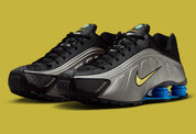 Nike Shox R4 Brazil avec tige en mesh noir et empiècements synthétiques, détails Canary et Light Photo Blue, amorti Nike Shox et semelle extérieure en caoutchouc.