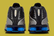 Nike Shox R4 Brazil avec tige en mesh noir et empiècements synthétiques, détails Canary et Light Photo Blue, amorti Nike Shox et semelle extérieure en caoutchouc.