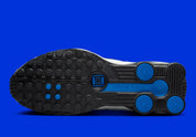 Nike Shox R4 Orlando avec tige en cuir synthétique blanc, détails noirs et bleus, amorti Nike Shox à quatre colonnes et semelle extérieure en caoutchouc.