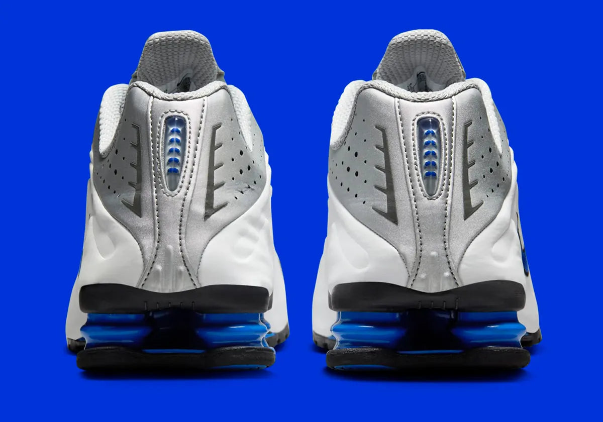 Nike Shox R4 Orlando avec tige en cuir synthétique blanc, détails noirs et bleus, amorti Nike Shox à quatre colonnes et semelle extérieure en caoutchouc.