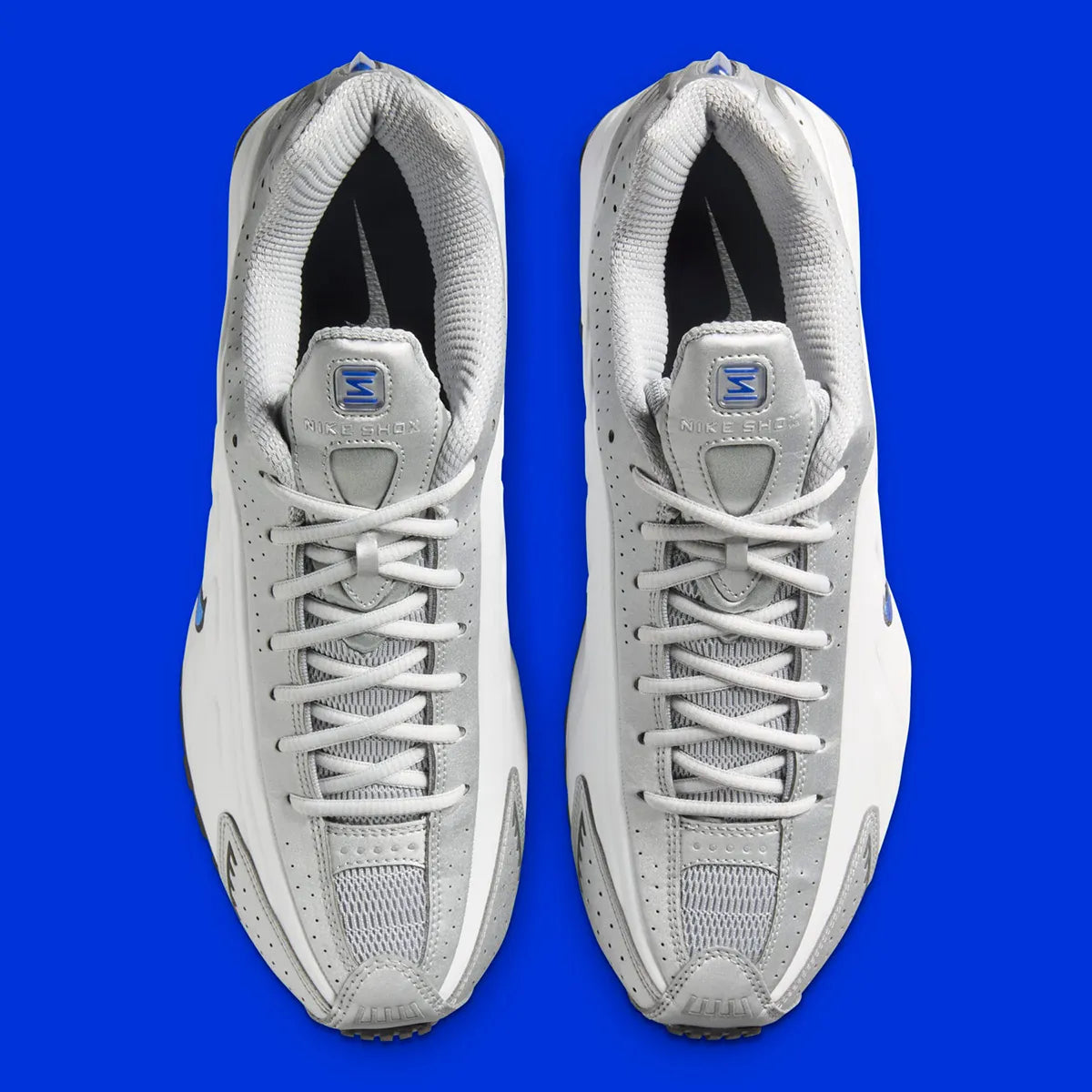 Nike Shox R4 Orlando avec tige en cuir synthétique blanc, détails noirs et bleus, amorti Nike Shox à quatre colonnes et semelle extérieure en caoutchouc.