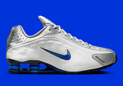 Nike Shox R4 Orlando avec tige en cuir synthétique blanc, détails noirs et bleus, amorti Nike Shox à quatre colonnes et semelle extérieure en caoutchouc.