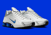 Nike Shox R4 Orlando avec tige en cuir synthétique blanc, détails noirs et bleus, amorti Nike Shox à quatre colonnes et semelle extérieure en caoutchouc.