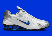 Nike Shox R4 Orlando avec tige en cuir synthétique blanc, détails noirs et bleus, amorti Nike Shox à quatre colonnes et semelle extérieure en caoutchouc.