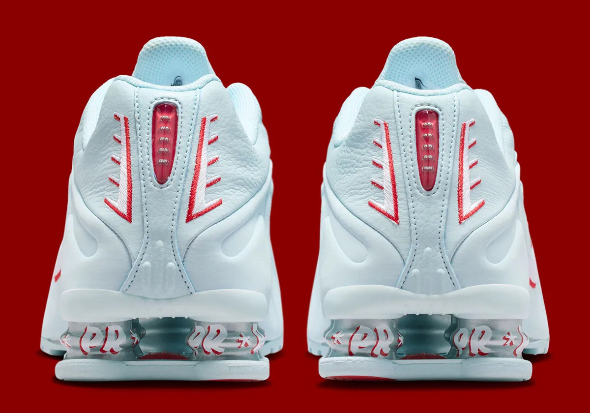 Nike Shox R4 Puerto Rico avec tige Glacier Blue en cuir synthétique, détails University Red et Metallic Silver, graphismes PR, porte-bonheur Vejigante et amorti Nike Shox à quatre colonnes.