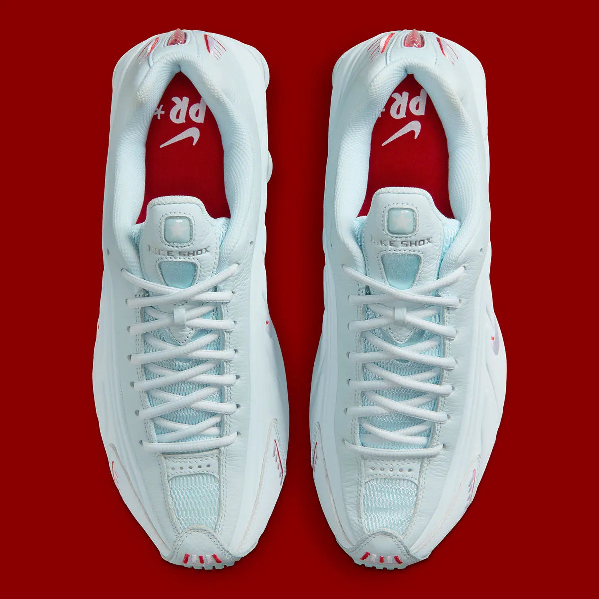 Nike Shox R4 Puerto Rico avec tige Glacier Blue en cuir synthétique, détails University Red et Metallic Silver, graphismes PR, porte-bonheur Vejigante et amorti Nike Shox à quatre colonnes.