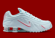 Nike Shox R4 Puerto Rico avec tige Glacier Blue en cuir synthétique, détails University Red et Metallic Silver, graphismes PR, porte-bonheur Vejigante et amorti Nike Shox à quatre colonnes.