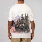 Nike x NOCTA Opal Reels Tee White, tee-shirt blanc en coton avec illustration paysage et pêcheur, détails multicolores et Swoosh orange.