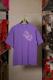 T-shirt Global Sneakers Concrete Bloom en coton premium 230 g fabriqué au Portugal, avec illustration florale signature sur la poitrine et dans le dos, disponible en Noir, Blanc, Lila et Verdeau.