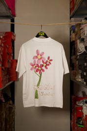 T-shirt Global Sneakers Concrete Bloom en coton premium 230 g fabriqué au Portugal, avec illustration florale signature sur la poitrine et dans le dos, disponible en Noir, Blanc, Lila et Verdeau.