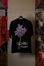 T-shirt Global Sneakers Concrete Bloom en coton premium 230 g fabriqué au Portugal, avec illustration florale signature sur la poitrine et dans le dos, disponible en Noir, Blanc, Lila et Verdeau.