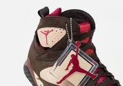 Vue zoomée sur les détails latéraux de la Air Jordan 7 Retro Patta Shimmer AT3375-200 en cuir et suède marron avec accents Tough Red, Jumpman brodé et branding Patta sur la semelle.