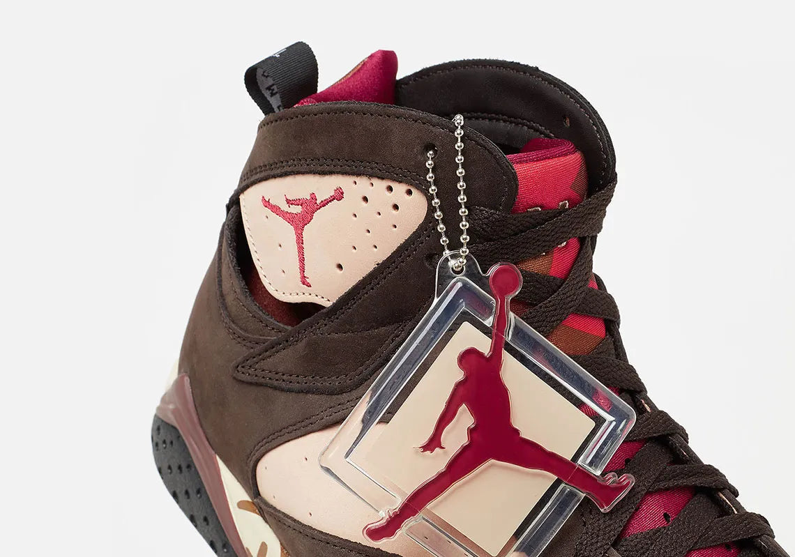 Vue zoomée sur les détails latéraux de la Air Jordan 7 Retro Patta Shimmer AT3375-200 en cuir et suède marron avec accents Tough Red, Jumpman brodé et branding Patta sur la semelle.