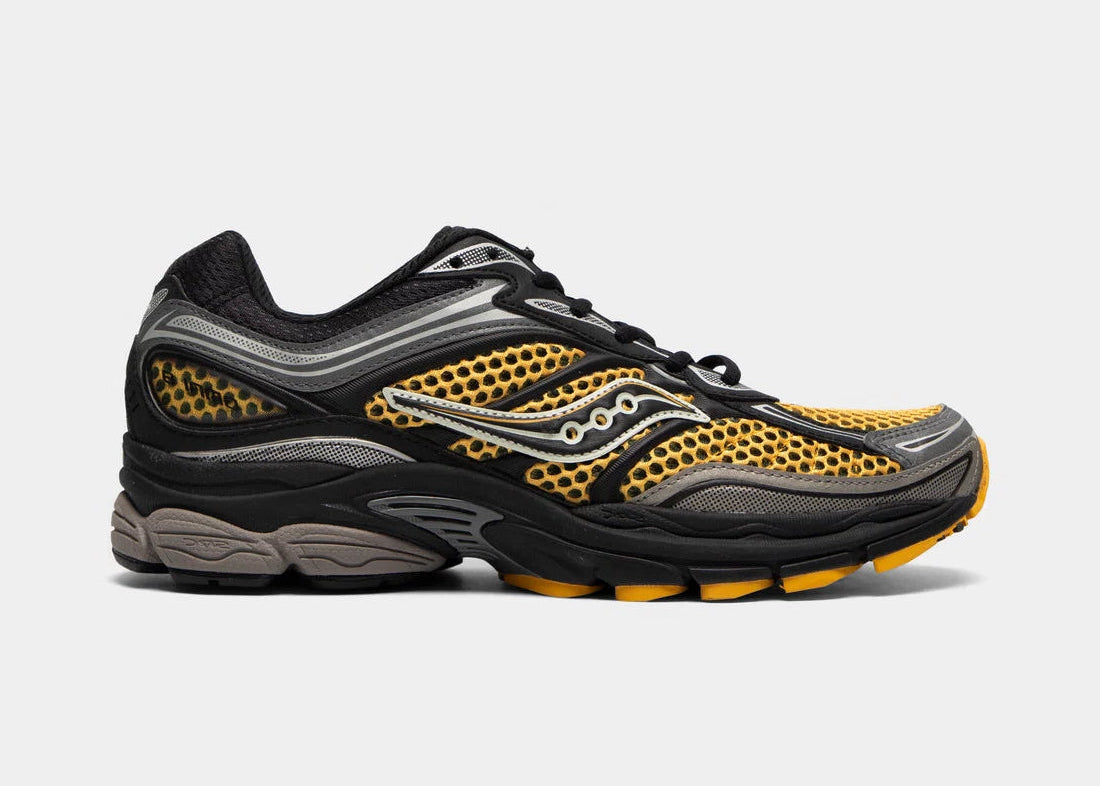 Saucony ProGrid Omni 9 Black Gold, sneaker running rétro noire et dorée en mesh avec empiècements techniques et semelle à technologie Grid vue de profil. 