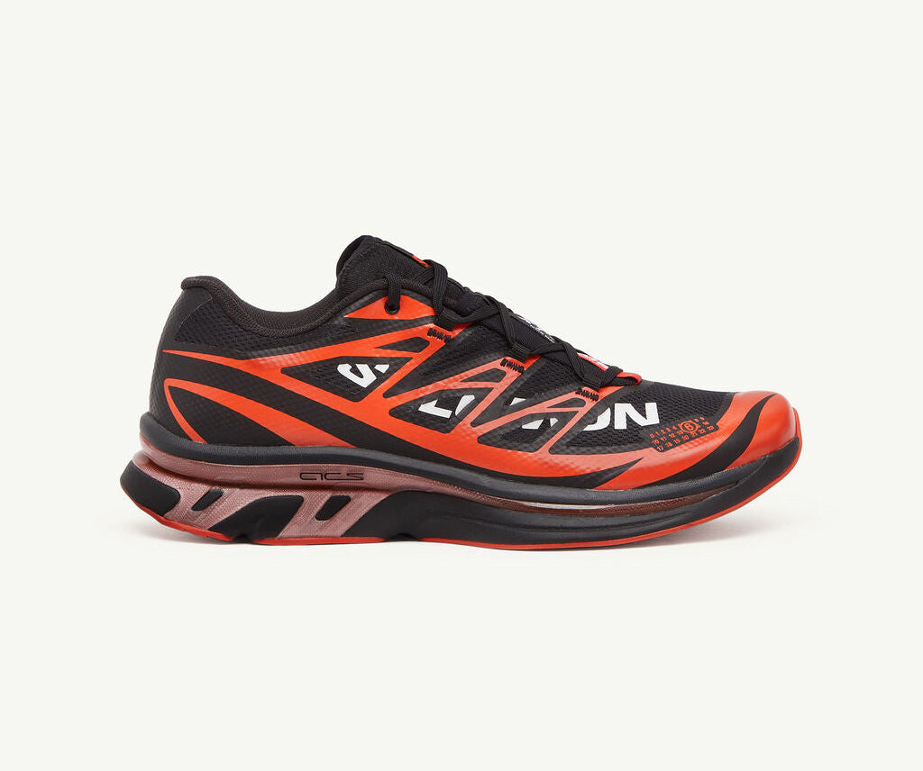 Image de la Salomon XT-6 MM6 Maison Margiela Black Cherry Tomato, sneaker noire avec accents rouge vif, tige en mesh technique, renforts TPU, semelle Contagrip®, laçage Quicklace. Vue de profil.