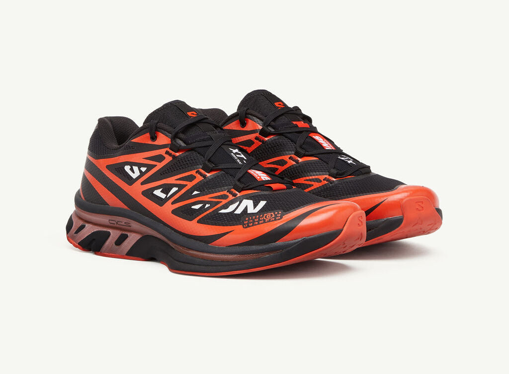 Image de la Salomon XT-6 MM6 Maison Margiela Black Cherry Tomato, sneaker noire avec accents rouge vif, tige en mesh technique, renforts TPU, semelle Contagrip®, laçage Quicklace. Vue de 3/4 face.