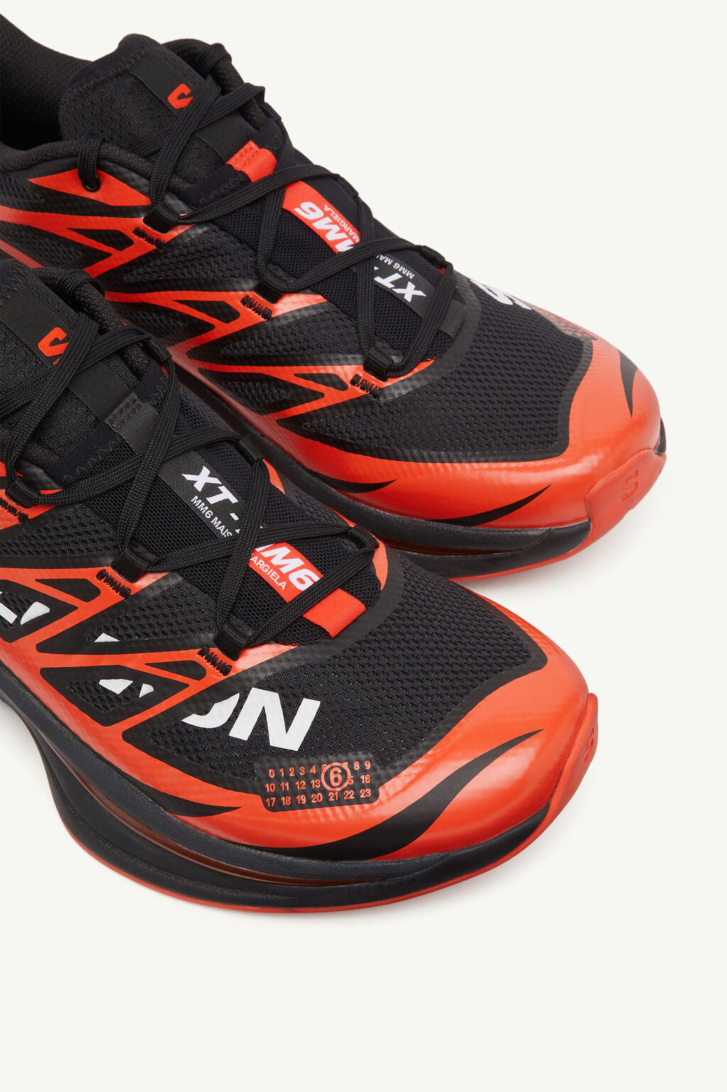 Image de la Salomon XT-6 MM6 Maison Margiela Black Cherry Tomato, sneaker noire avec accents rouge vif, tige en mesh technique, renforts TPU, semelle Contagrip®, laçage Quicklace. Vue de dessus sur l'avant de la paire.