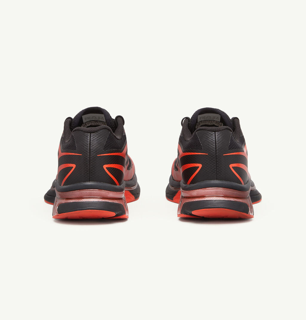 Image de la Salomon XT-6 MM6 Maison Margiela Black Cherry Tomato, sneaker noire avec accents rouge vif, tige en mesh technique, renforts TPU, semelle Contagrip®, laçage Quicklace. Vue de derrière.