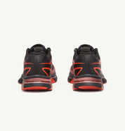 Image de la Salomon XT-6 MM6 Maison Margiela Black Cherry Tomato, sneaker noire avec accents rouge vif, tige en mesh technique, renforts TPU, semelle Contagrip®, laçage Quicklace. Vue de derrière.