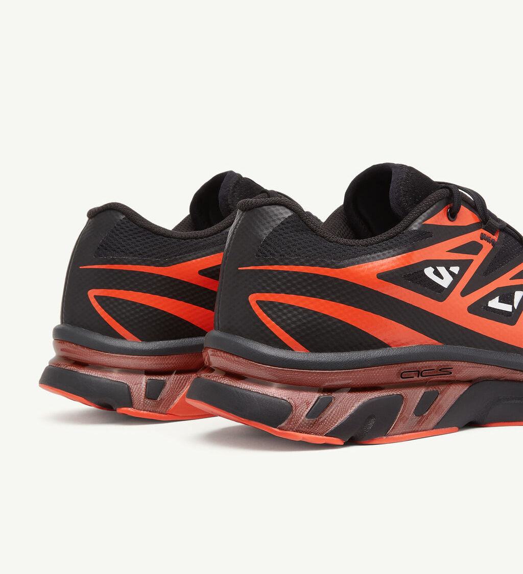 Image de la Salomon XT-6 MM6 Maison Margiela Black Cherry Tomato, sneaker noire avec accents rouge vif, tige en mesh technique, renforts TPU, semelle Contagrip®, laçage Quicklace. Vue de 3/4 arrière.