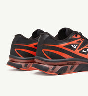 Image de la Salomon XT-6 MM6 Maison Margiela Black Cherry Tomato, sneaker noire avec accents rouge vif, tige en mesh technique, renforts TPU, semelle Contagrip®, laçage Quicklace. Vue de 3/4 arrière.