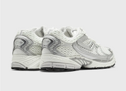 Saucony ProGrid Ride 1 Ivory Silver avec tige en mesh respirant, empiècements synthétiques ivoire et argent métallisé, technologie ProGrid et semelle extérieure en caoutchouc.